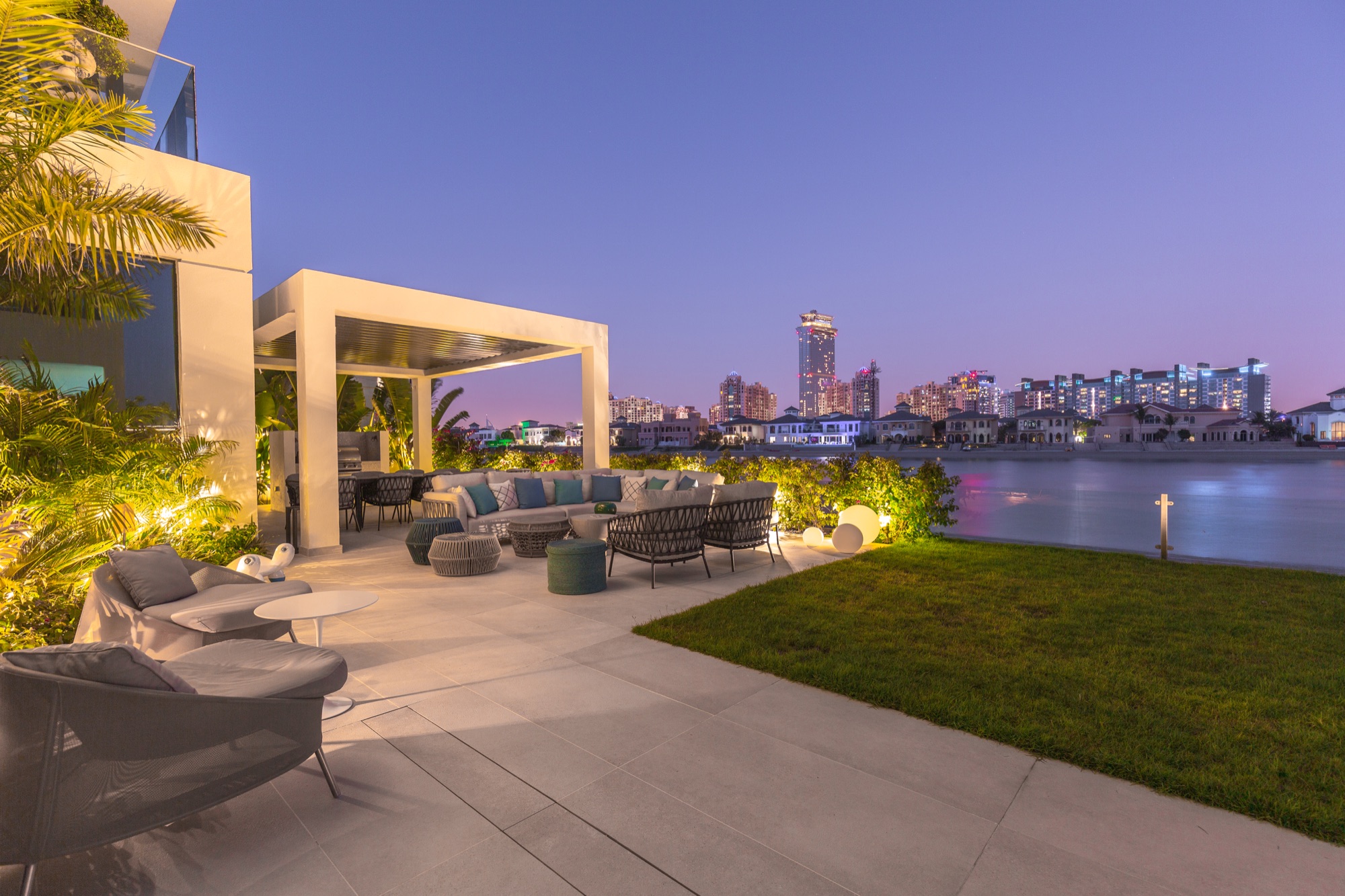 Luxury waterfront villa terrace with architectural pergola and landscaping